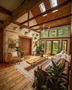 a living room filled with lots of furniture and plants on top of wooden flooring