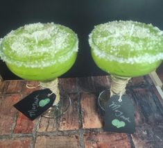 two margaritas are sitting on the table with tags