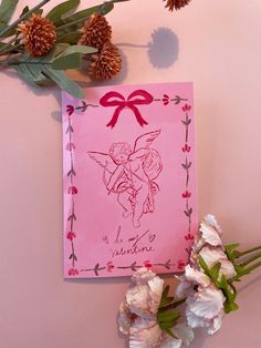 a pink card with an angel on it next to flowers