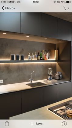 a modern kitchen with stainless steel sink and countertop, lighted by recessed lighting