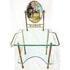 a glass and metal table with a mirror on it's back end, in front of a white backdrop