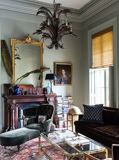 a living room filled with furniture and a chandelier hanging from the ceiling over a fire place