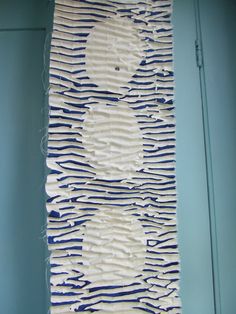 a piece of art that is made out of paper and yarn on a blue wall