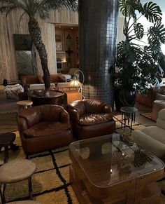 a living room filled with lots of furniture next to a tall plant in the corner