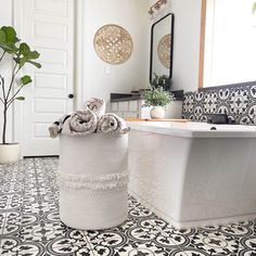 a bathroom with black and white tile flooring next to a bathtub in the corner