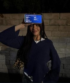 a woman holding up a cell phone to her face with the screen on it's head