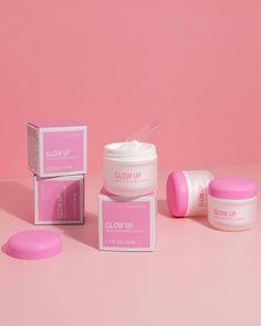 three pink boxes and two white containers on a pink background with the words glow up