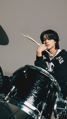 a young man sitting on top of a black motorcycle next to a drum kit and drumstick