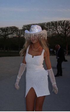 a woman in a white dress and hat is walking down the street with her legs spread out