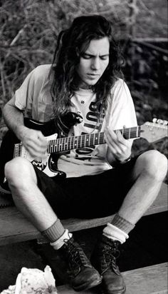 a man sitting on a bench playing an electric guitar