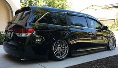 a black minivan parked on the side of a driveway in front of a house