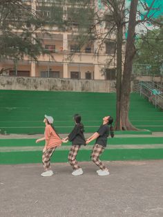 three young people are dancing in front of some stairs and trees on the side walk