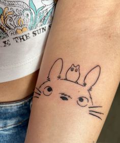 a woman's arm with a tattoo on it that has an image of a cat and bird sitting on her head