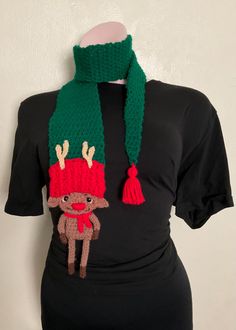 a woman wearing a knitted christmas hat and scarf with a reindeer on the front