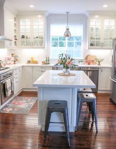 a kitchen with two stools in front of the island