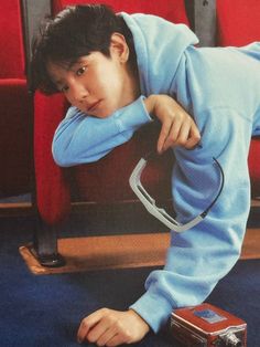 a young boy in blue tracksuits leaning against a red chair with his hand on the ground