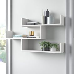 two white shelves with plants and books on them