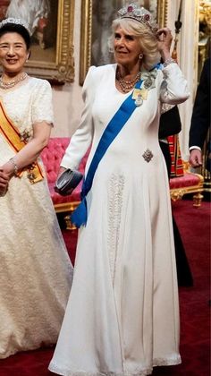 the queen and prince are walking together in their official regal gowns, tiaras and sashes