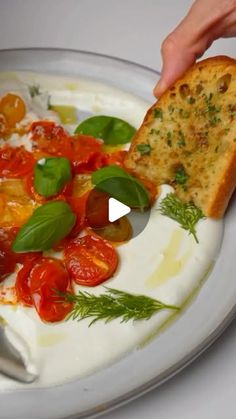 a plate with bread and tomatoes on it, being held by someone's hand