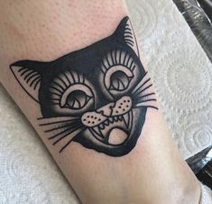 a black and white cat tattoo on the leg with an evil look to it's face