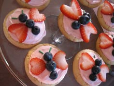 some cookies with strawberries and blueberries are on a glass platter, ready to be eaten