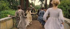 several women in dresses walking down a path