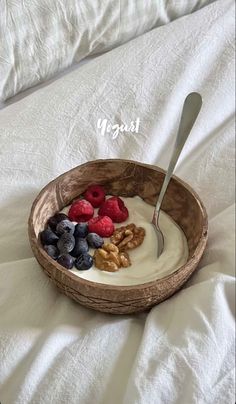 a bowl filled with yogurt and berries on top of a white bed sheet