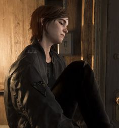 a woman sitting on top of a wooden floor next to a door