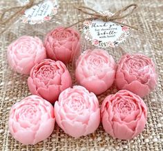 six pink flowers are sitting on a burlocked tablecloth with twine tags