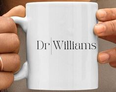 a person holding a coffee mug with the word dr williams on it in front of their face