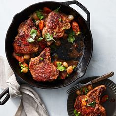 two pans filled with meat and vegetables on top of a white tablecloth next to a fork