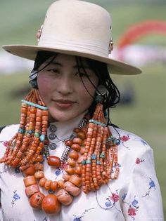 a woman wearing a white hat and orange necklace