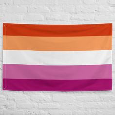 a white brick wall with an orange, pink and purple striped flag hanging on it