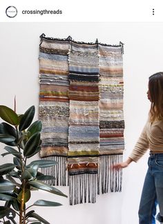 a woman is standing in front of a wall hanging