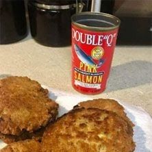 three patties on a plate next to a can of pink salmon