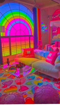 a living room filled with lots of furniture and rainbow colored curtains on the window sill