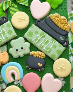 some decorated cookies are laying on a green tablecloth with shamrocks and other decorations