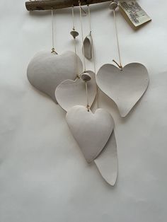 three white heart shaped ornaments hanging from a tree branch with a book on the other side