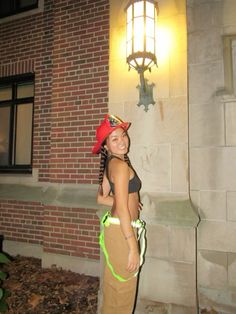 a woman standing in front of a brick building wearing a red hat and green leash