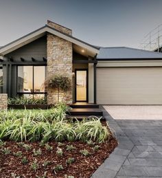 a house that is in the middle of some grass and plants on the front lawn