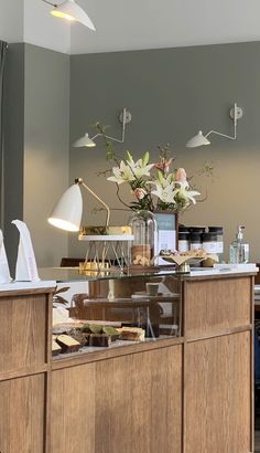 a counter with some food on it and flowers in a vase at the front desk