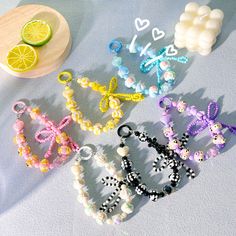 four bracelets with beads and fruit on a table next to a bowl of lemons