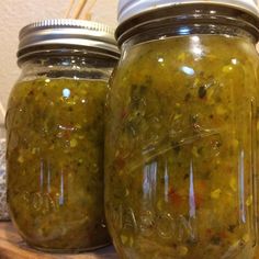 two jars filled with pickles sitting on top of a table