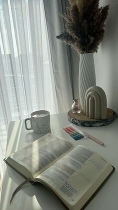 an open book sitting on top of a table next to a cup