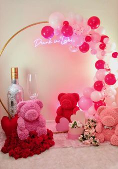 pink and red teddy bears sitting next to each other on a white carpet with balloons