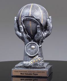 a trophy with a basketball on it sitting on top of a black table in front of a gray background