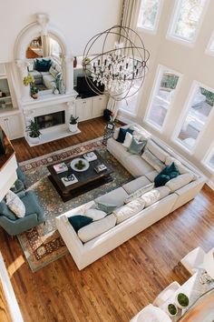 an aerial view of a living room with couches, coffee table and chandelier