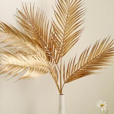 a plant in a white vase sitting on top of a table next to a wall