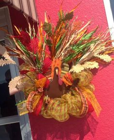 a clock that is hanging on the side of a building with autumn decorations around it