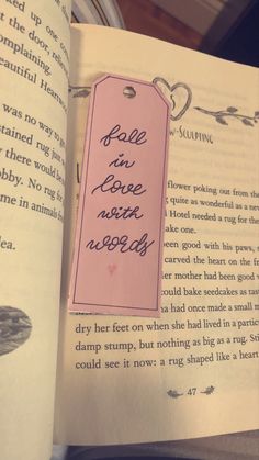 an open book with a pink tag that says fall in love never ends on it